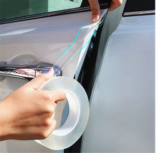 A hand holding a large, clear roll of double sided adhesive tape while applying a strip to the edge of a white car door