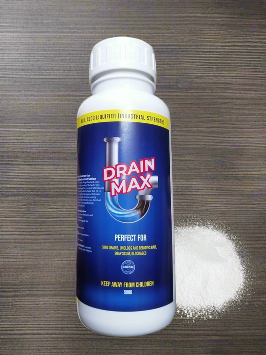 A bottle of Drain Max clog remover with its contents spilled out in front of it on a wooden surface.