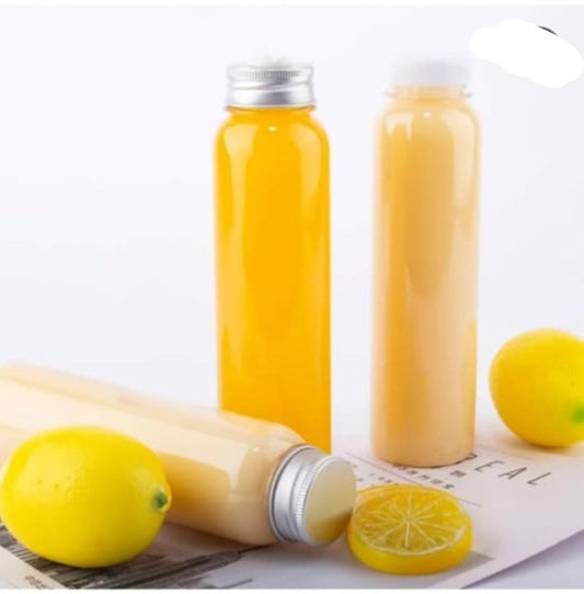 The image shows a set of six clear plastic shot bottles with two bottles filled with a yellow liquid, presumably a ginger lemon shot. There are lemons and a slice of lemon visible beside the bottles.