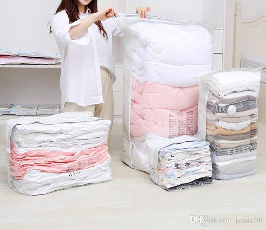 A woman zipping a large white compression storage bag containing pink bedding, surrounded by several other compressed bags of clothes and blankets, demonstrating space saving.