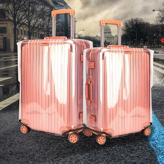 Two pink metallic suitcases covered with clear plastic protectors.