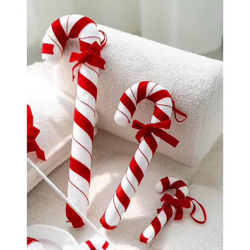 Red and white striped candy canes with bows on a white surface