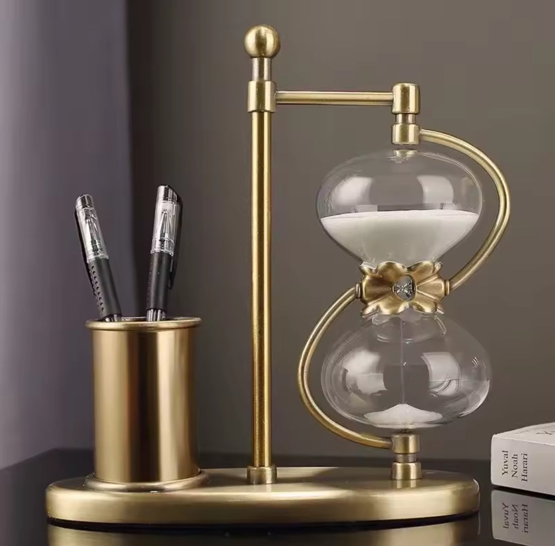 Decorative hourglass with a gold base and pen holder
