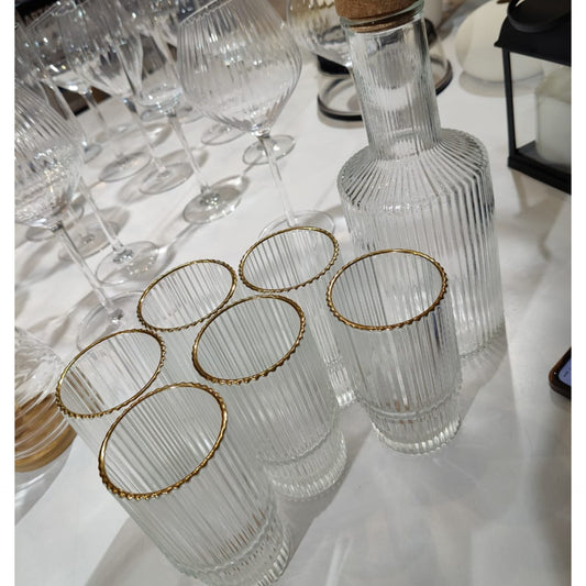 A set of six clear ribbed glass tumblers with a gold rim and a tall matching ribbed glass decanter with a cork stopper.