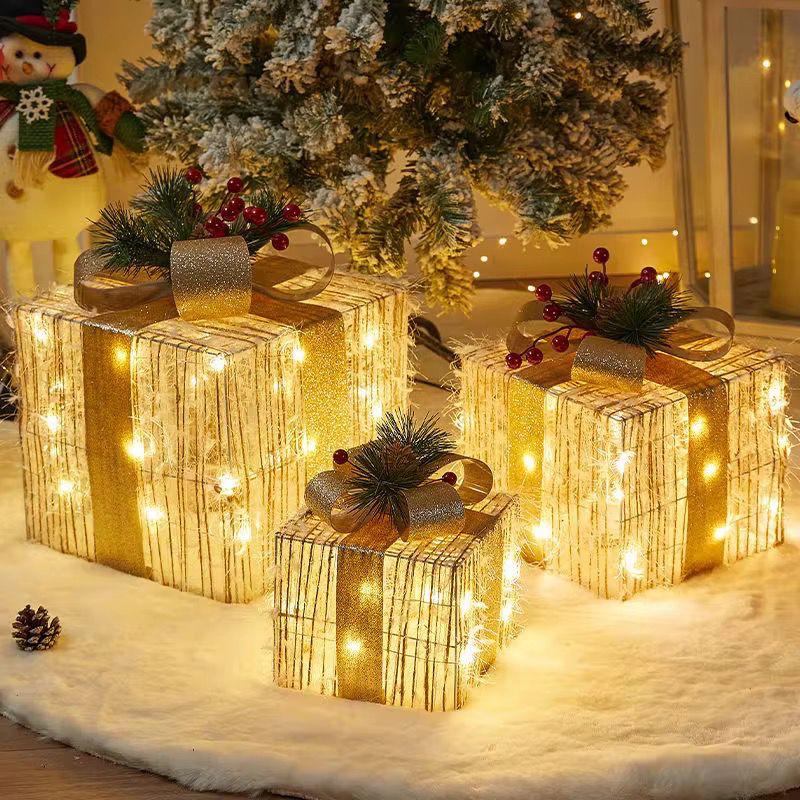 Set of three glowing golden mesh Christmas gift boxes with bows and lights.