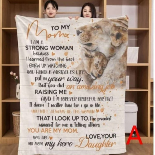 Fleece throw blanket featuring a printed message about a strong mother and a graphic of a lioness with her cub on a rustic wood background.