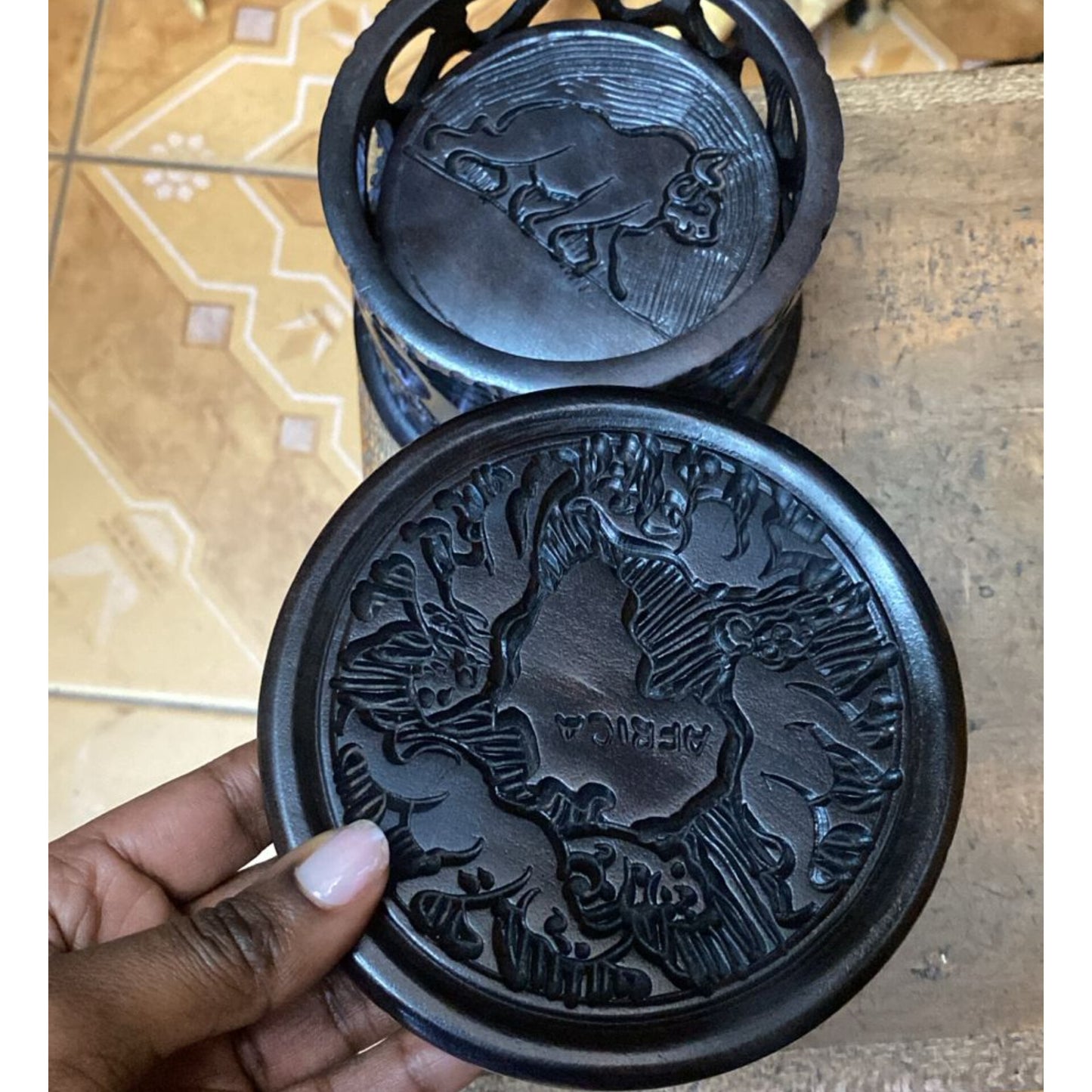Handcrafted ebony wood coaster set with stand. One coaster shows a carved map of Africa; the stand shows a carved Big Five animal.