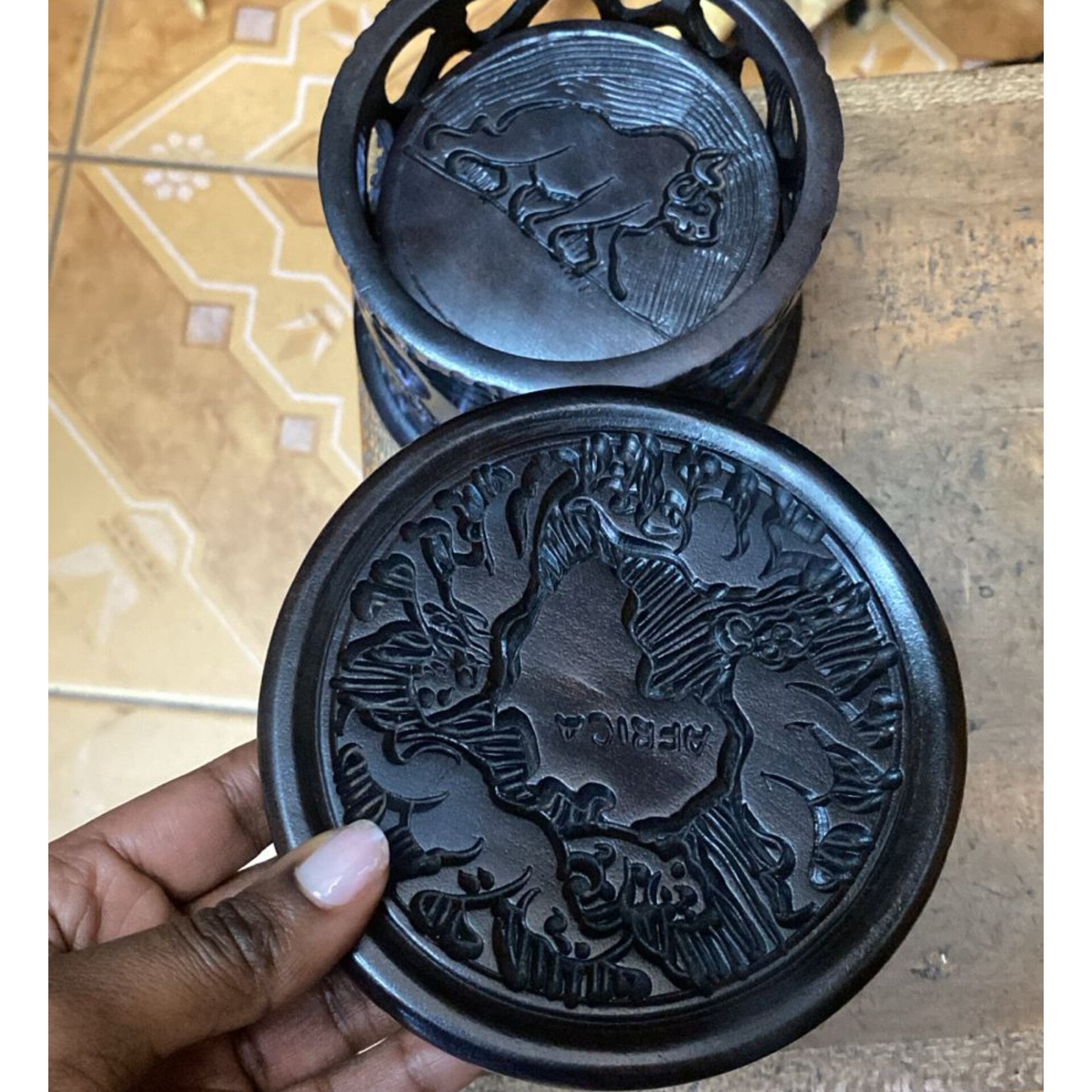 Handcrafted ebony wood coaster set with stand. One coaster shows a carved map of Africa; the stand shows a carved Big Five animal.