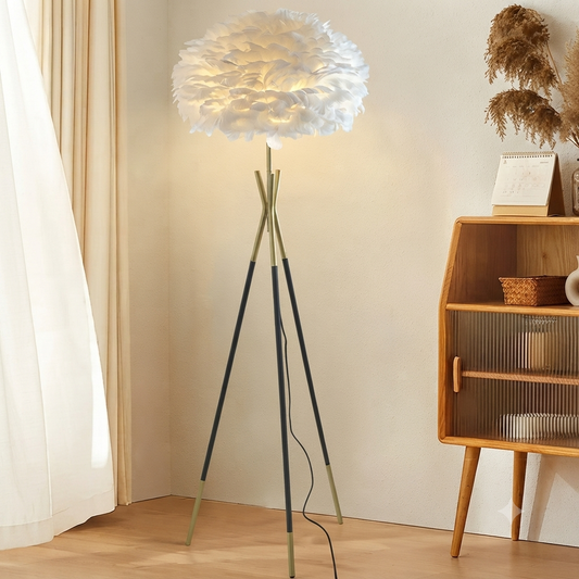 A tripod floor lamp with a fluffy white feather-like shade and dark gray legs.