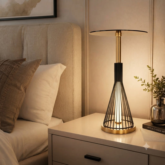 A table lamp with a gold and black wireframe cone base and a round disc shade.