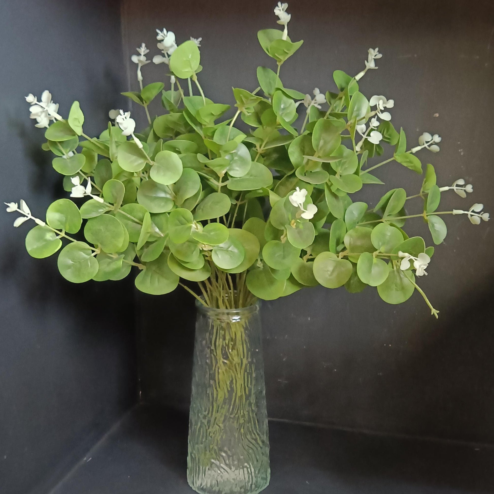 Artificial eucalyptus stems in a textured green glass vase