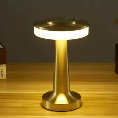 A gold dumbbell shaped cordless table lamp