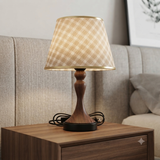 A table lamp with a beige and white plaid patterned shade, a dark brown wooden base, and a black circular base.