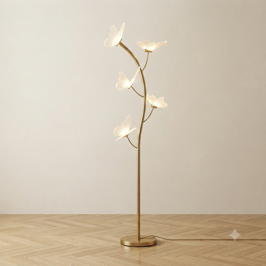 A modern floor lamp with a slender gold-toned branch-like stand and four translucent white butterfly-shaped light diffusers.