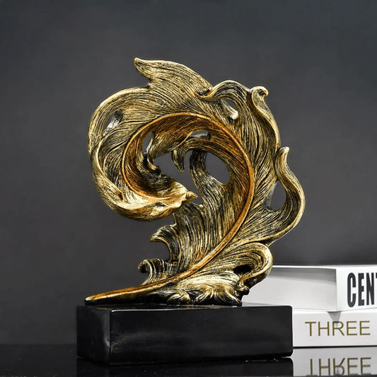 Abstract resin sculpture shaped like a curved feather with an antique gold and black distressed finish on a black base.