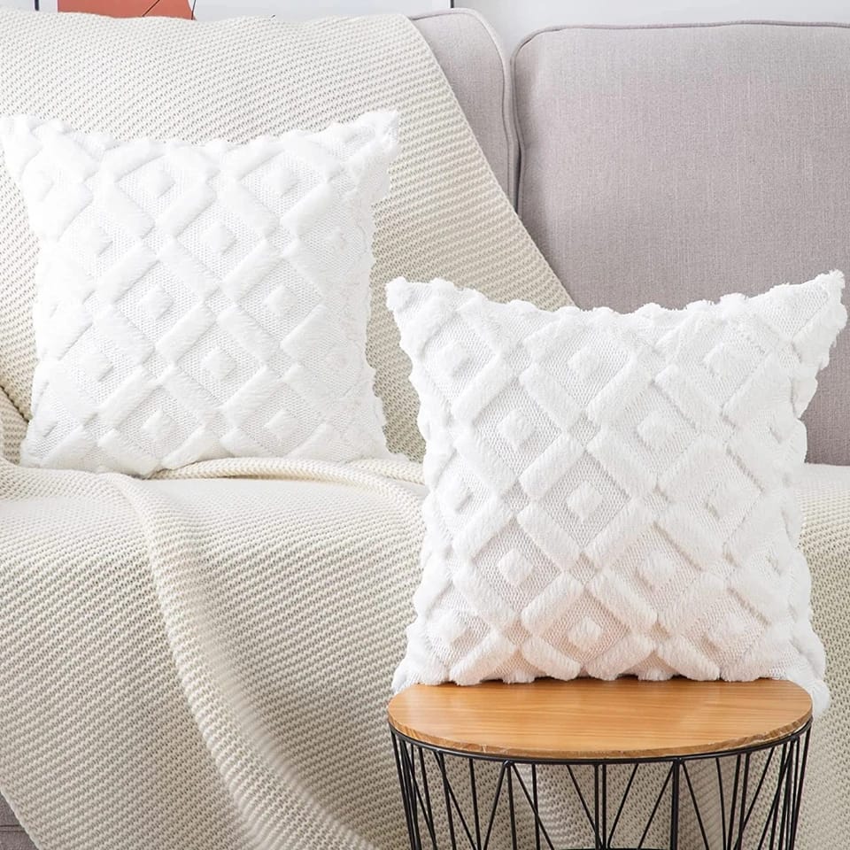 Two white square throw pillow covers with a raised geometric diamond tufted pattern.
