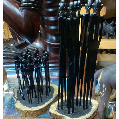 A group of slender, dark hand-carved Wooden stick figures standing upright on natural wood bases.