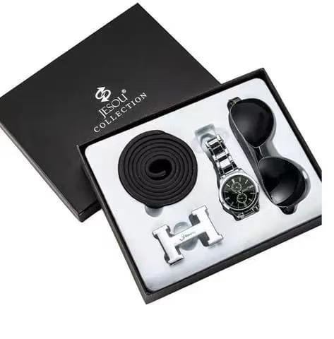 black gift box containing a silver wristwatch with a dark face, a rolled black belt, and a pair of dark sunglasses, with the lid of the box resting next to it.