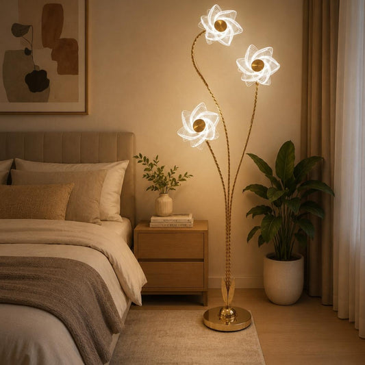 A modern floor lamp with three glowing flower-shaped shades and twisted gold-toned stems.