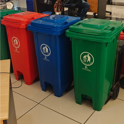 Three tall, rectangular 120-liter pedal waste bins in bright red, blue, and green, each with a white recycling symbol, standing in a row on a tiled floor.