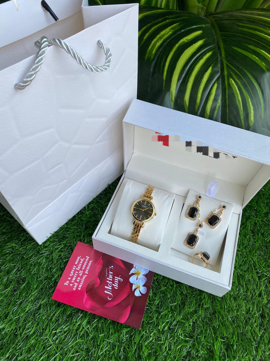 Gold-tone women's watch and black-stone jewelry set in a white presentation box with a Mother's Day card and white gift bag.