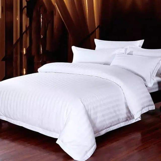 A fully made bed featuring a white striped duvet cover, white pillows, and a white bed sheet.